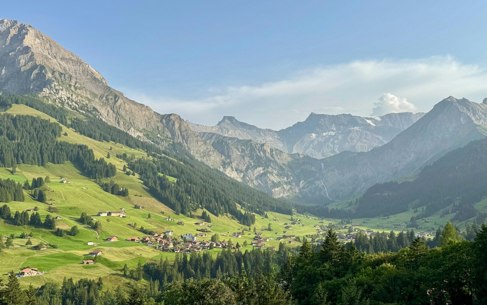 Lush green valley surrounded by majestic mountains under a clear sky