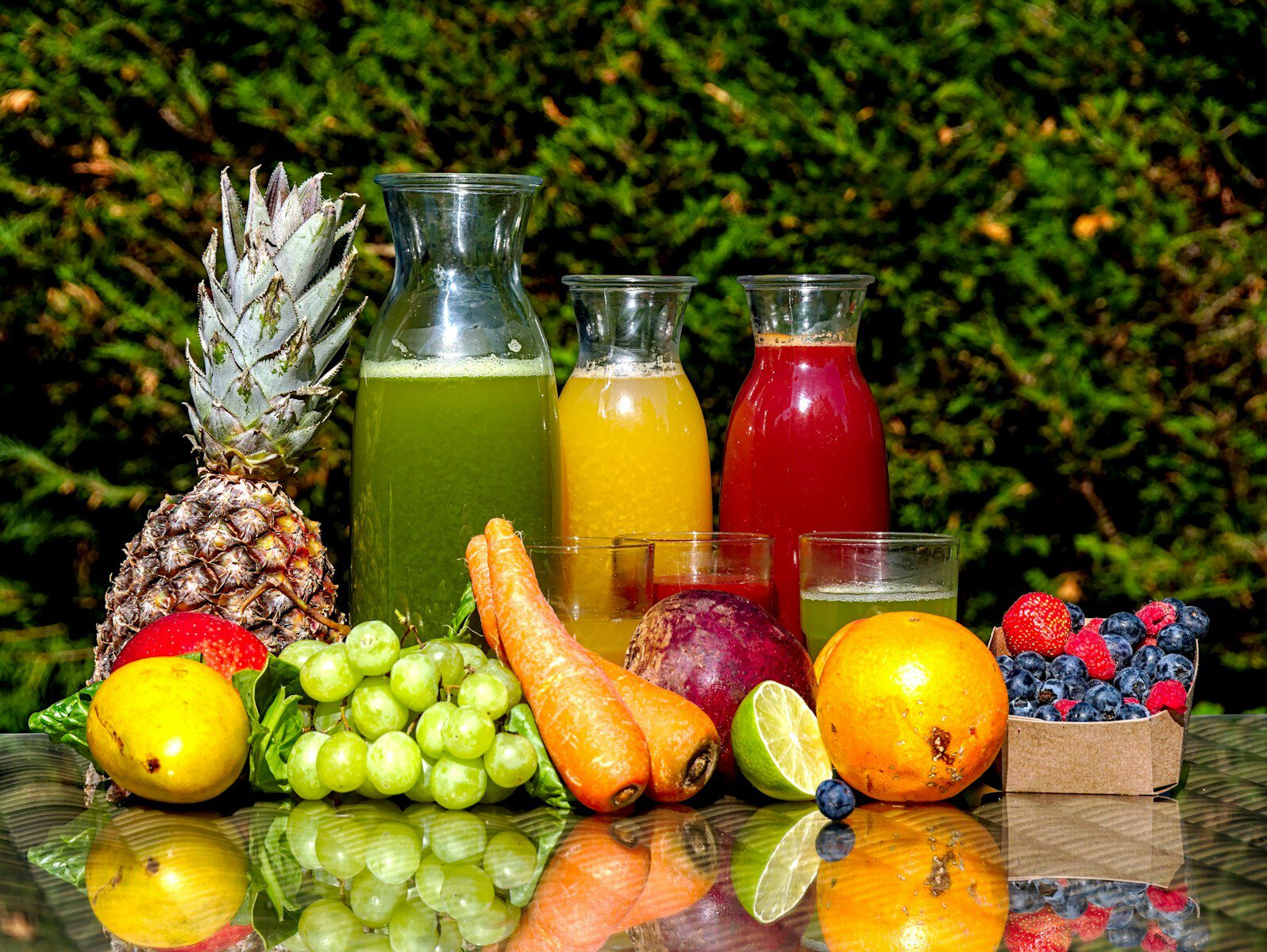 Fresh fruit and vegetable juices in glass bottles with produce on a table